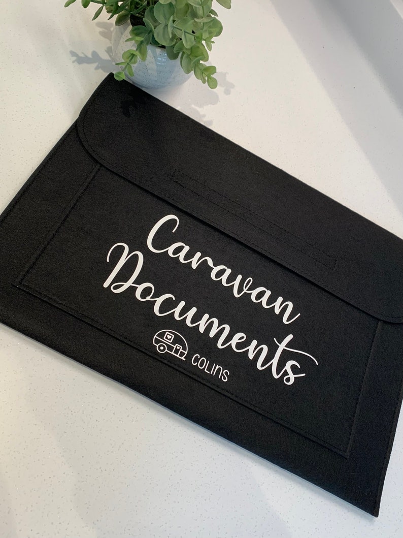 May include: Black felt folder with the text "Caravan Documents" and a small caravan icon. The text "COLINS" is below the icon.