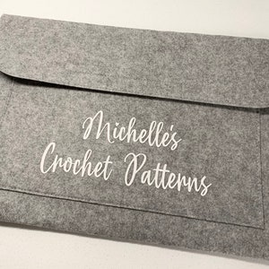 May include: A grey felt envelope with a white inscription that reads "Michelle's Crochet Patterns".