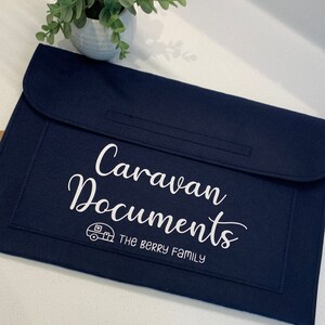 May include: A dark blue felt folder with a white embroidered design that says "Caravan Documents" and "The Berry Family". A small white caravan icon is also embroidered on the folder.