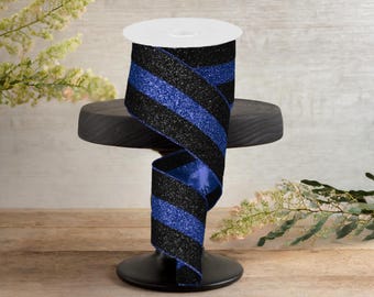 May include: Black and royal blue glitter ribbon with stripes. The ribbon is on a black stand.