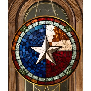 May include: A stained glass window depicting the Texas state flag. The flag is made up of a blue background with a white five-pointed star in the center. The star is surrounded by a red and white stripe.