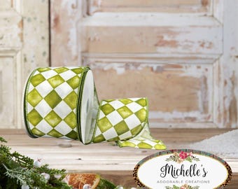 Pode incluir: Um rolo de fita com arame apresentando um padrão repetitivo de diamantes verdes e brancos. A fita tem um acabamento de tecido texturizado e bordas costuradas em verde escuro. Um adesivo oval com o texto Michelle's ADORABLE CREATIONS é visível.