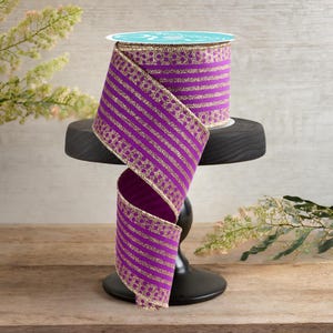 Könnte beinhalten: Lila und goldfarbenes gestreiftes Band mit einem gepunkteten Muster. Das Band ist um einen schwarzen Ständer gewickelt.