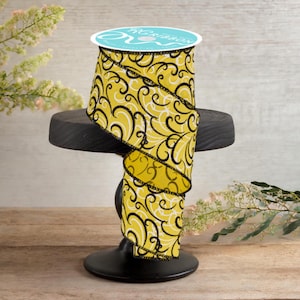 Könnte beinhalten: Gelb-schwarzes gemustertes Band mit weißem Hintergrund. Das Band ist gerollt und auf einem schwarzen Ständer ausgestellt.