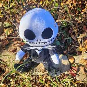 Op de afbeelding: Een pluche speelgoed van Jack Skellington uit de film Nightmare Before Christmas. Het speelgoed draagt een zwart-wit gestreept pak en heeft een wit gezicht met zwarte ogen en een gestikte mond.