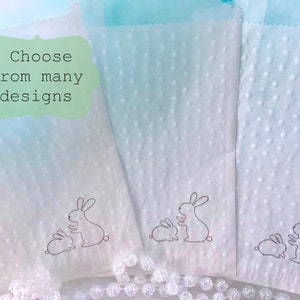 May include: White paper gift bags with a dotted texture and a line drawing of a mother and baby bunny. The bags have a light blue and white gradient background. Text on the image says "Choose from many designs".