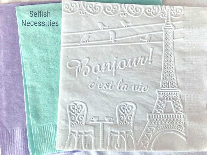 White, lavender and mint cocktail napkins are embossed with a French cafe scene to give texture. The Eiffel Tower is displayed along with a cafe table and chairs and the word Bonjour!