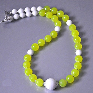 May include: A white and yellow jade bead necklace with a silver clasp. The necklace is made of round beads and has a larger white bead in the centre.