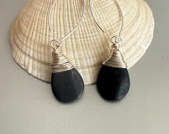 May include: A pair of silver dangle earrings with black stone drops wrapped in silver wire.