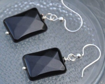 May include: A pair of black onyx earrings with silver hooks. The earrings are rectangular in shape and have a faceted design.