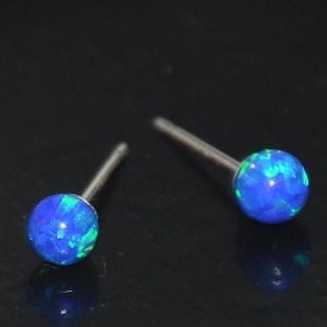 May include: A pair of silver stud earrings with blue and green opal stones.