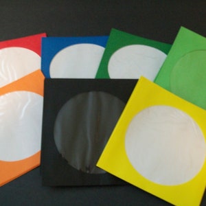 May include: Assortment of eight CD sleeves in various colors, including red, orange, yellow, green, blue, and black. Each sleeve has a clear window to display the CD.