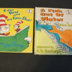 May include: Two children's books, one titled "I Can Read with My Eyes Shut!" by Dr. Seuss, featuring a cat in a red and white striped hat reading a green book, and the other titled "A Fish Out Of Water" by Helen Palmer, illustrated by P.D. Eastman, featuring a goldfish jumping out of water.
