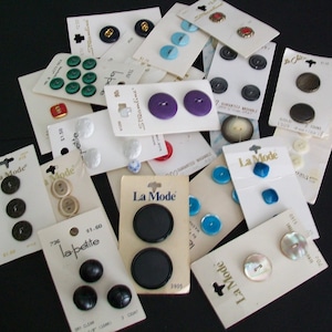 May include: Assortment of vintage buttons on cards, including black, white, green, blue, purple, and gold buttons. Some cards have the text "La Mode" and "la-petite".
