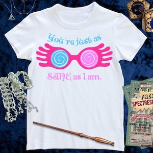 May include: White t-shirt with a pink and blue graphic of a pair of glasses with a pink hand on each side. The text "You're just as SANE as I am." is printed below the graphic.