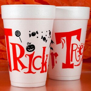 May include: Two white foam cups with red "Trick or Treat" lettering and Halloween-themed graphics. The cups feature a lollipop, candies, a jack-o'-lantern, and bats. Perfect for Halloween parties and events.