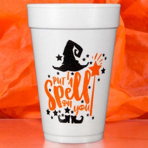 May include: White foam cup with the phrase "Put a Spell on You" in orange script, along with a black witch hat, stars, and a magic wand design. The cup is decorated with Halloween-themed graphics.