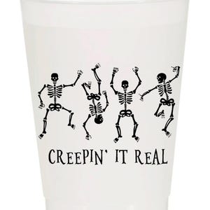 May include: A white plastic cup with a black graphic of dancing skeletons. The phrase "CREEPIN' IT REAL" is printed in black below the skeletons. Ideal for Halloween or spooky-themed parties.