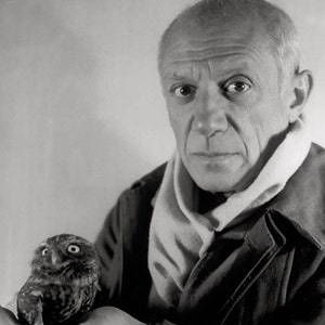 May include: A black and white photo of a man with a white scarf around his neck holding a small brown owl in his hand.