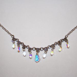 May include: A silver chain necklace with iridescent crystal teardrop pendants.