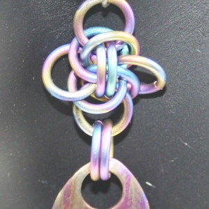 May include: A pair of iridescent earrings with a multi-colored, knotted design and a teardrop-shaped pendant.