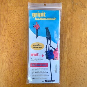 May include: A white package with a blue and yellow logo that reads "gripit for a secure lower grip". The package shows a person using a ski pole with a blue and black grip. The text on the package reads "The add-on 2nd grip for all poles" and "the Gripit story".
