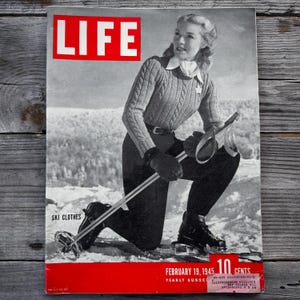 May include: Vintage LIFE magazine cover from February 19, 1945, featuring a woman in ski clothes. The cover has a red border with the magazine title in white. The woman is wearing a cable-knit sweater, black pants, and ski boots, holding ski poles.