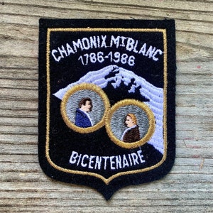 May include: Black embroidered patch with gold trim, depicting a mountain range and two portraits. The text reads "Chamonix Mt Blanc 1786-1986 Bicentenaire".