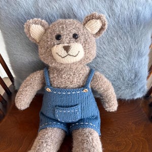 Handgebreide teddybeer van alpacabouclé met merino-outfit.