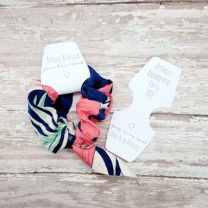Puede incluir: Una goma para el pelo floral con un estampado en azul marino, rosa y verde. Incluye dos etiquetas blancas. Una dice "To have & to hold your hair back", la otra "Britney's Bachelorette Party 2021."