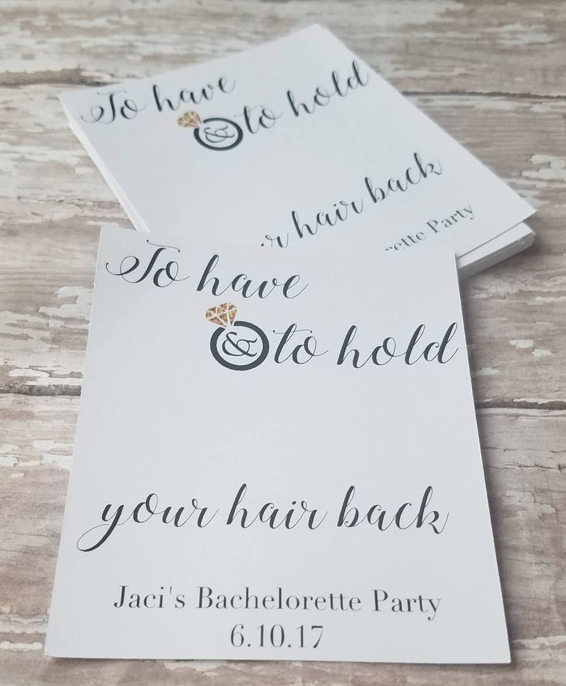 May include: White cards with black script text that reads "To have & to hold your hair back." A diamond ring graphic is above the text. The bottom of the card reads "Jaci's Bachelorette Party 6.10.17."