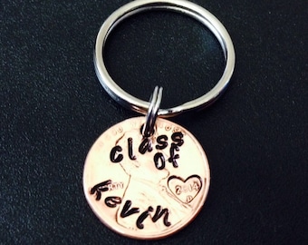 Può includere: Un portachiavi in ​​rame con le parole "Class of" e "Kevin" incise su di esso. Il centesimo ha un cuore con l'anno "2014" al suo interno.