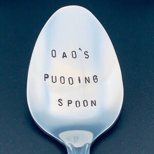 May include: A silver spoon with the words "Dad's Pudding Spoon" engraved on it.