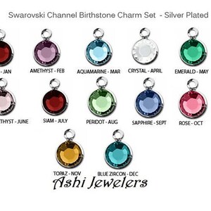 May include: A set of 12 silver-plated birthstone charms featuring Swarovski crystals. Each charm displays a different coloured crystal representing a different month of the year. The charms are labelled with the month and birthstone name.