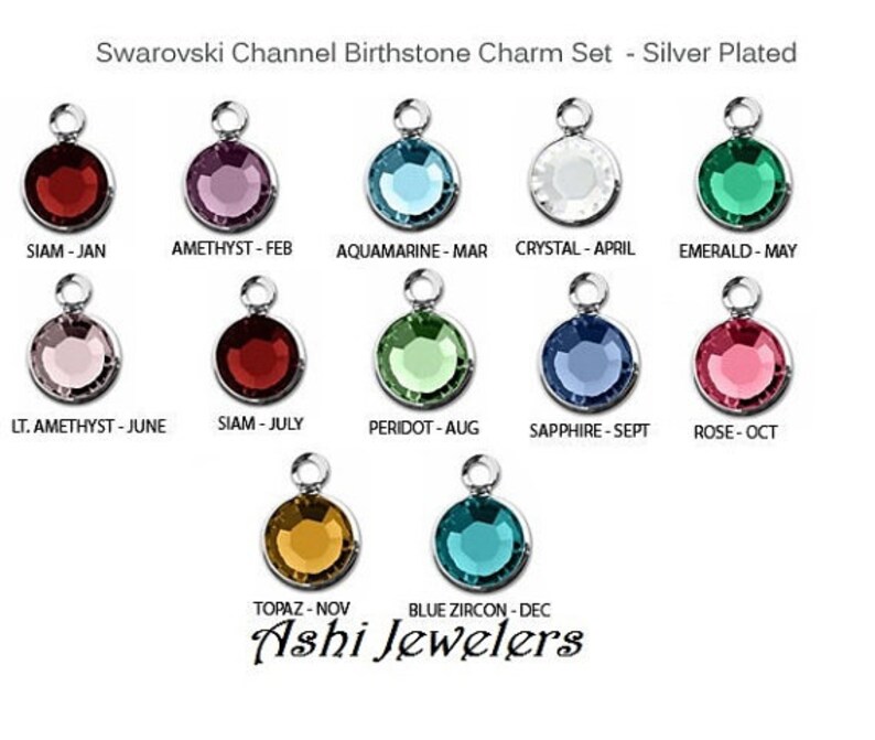 May include: A set of 12 silver-plated birthstone charms featuring Swarovski crystals. Each charm displays a different coloured crystal representing a different month of the year. The charms are labelled with the month and birthstone name.