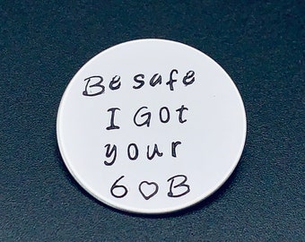 May include: White round disc with the text "Be safe I got your 6♡B" written in black.