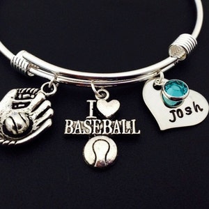 May include: Silver charm bracelet with a baseball glove, baseball, heart, and a heart charm with a turquoise stone and the name "Josh" engraved on it. The bracelet has the words "I love baseball" on it.