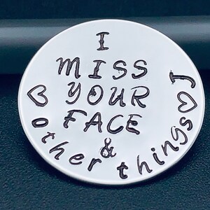 Peut inclure: Un charme en argent avec le texte "I miss your face & other things" et deux cœurs.