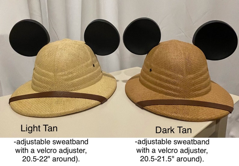 May include: Two safari hats with Mickey Mouse ears. The hat on the left is light tan and the hat on the right is dark tan. Both hats have adjustable sweatbands with velcro adjusters. The light tan hat is 20.5-22 inches around and the dark tan hat is 20.5-21.5 inches around.