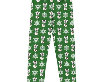 May include: Green leggings with a repeating pattern of snowmen and snowflakes. The snowmen have a mouse-like appearance, wearing red hats and scarves. The snowflakes are white. The leggings are made of a soft, stretchy material.