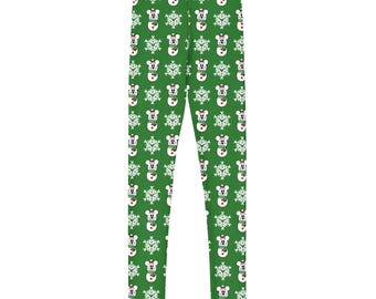 May include: Green leggings with a repeating pattern of white snowmen wearing hats and snowflakes. The snowmen have black eyes and a red nose. The leggings are made of a soft, stretchy material.
