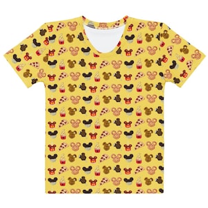 May include: Yellow V-neck t-shirt featuring a repeating pattern of Mickey Mouse-shaped treats, such as ice cream bars, pretzels, and pizza slices. The shirt has a white neckline and short sleeves.