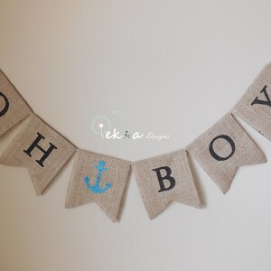 May include: A burlap banner with the words "Oh Boy" in black lettering. A blue anchor is in the center of the banner.
