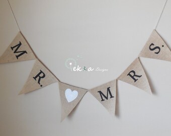 Könnte beinhalten: Ein Banner aus Jute mit den Worten "MR. & MRS." in schwarzer Schrift. Ein weißes Herz befindet sich zwischen den Worten.