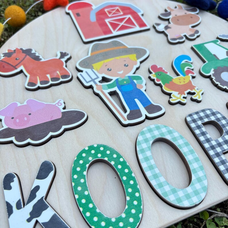 Pu&ograve; includere: Un puzzle in legno a tema fattoria con ritagli colorati di animali e personaggi della fattoria. Il puzzle include un fienile rosso, un cavallo marrone, un maiale rosa, un contadino, una mucca, un gallo e un trattore verde. Sono incluse anche le lettere "KOOP".