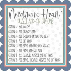 Pu&ograve; includere: Uno sfondo bianco con il testo "Needmore Heart" e "Puzzle Add-On Options". L'immagine elenca otto opzioni, inclusi componenti aggiuntivi come un espositore, un messaggio inciso e una confezione regalo. Il bordo &egrave; verde acqua, arancione e bianco, con un bordo smerlato blu.