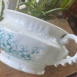 Pode incluir: Bacia de lavar antiga em porcelana branca com design floral turquesa. Possui uma alça decorativa e borda ondulada. Uma peça vintage para decoração de casa.