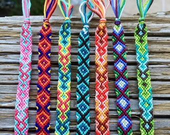 Puede incluir: Siete pulseras de amistad coloridas con diferentes patrones. Las pulseras están hechas con hilo de bordar de colores y están atadas en un nudo al final. Las pulseras están numeradas del 1 al 7.
