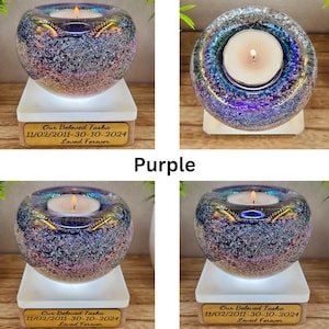 May include: A purple glass candle holder with a lit candle inside, resting on a white base. The candle holder has a speckled design and a gold-colored rim. A wooden plaque below reads "Our Beloved Tasha 11/02/2011-30-10-2024 Loved Forever."
