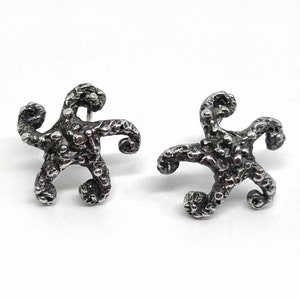 May include: A pair of silver starfish earrings with a textured, organic design.